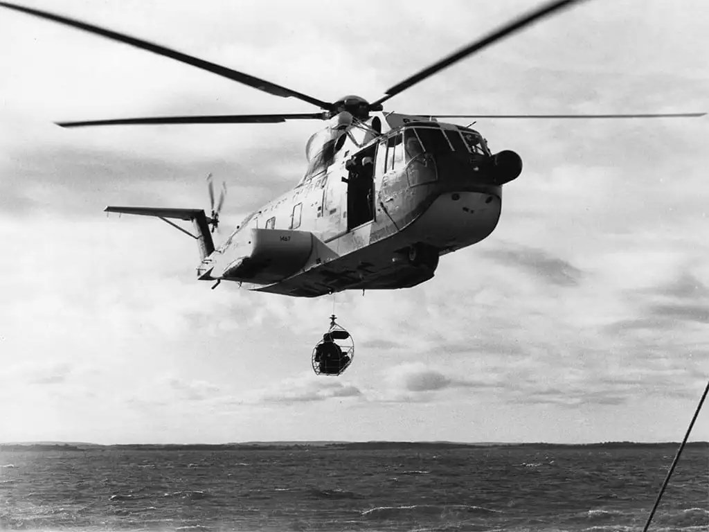 A vintage photo of a Coast Guard HH-3F “Pelican” making a hoist at sea.