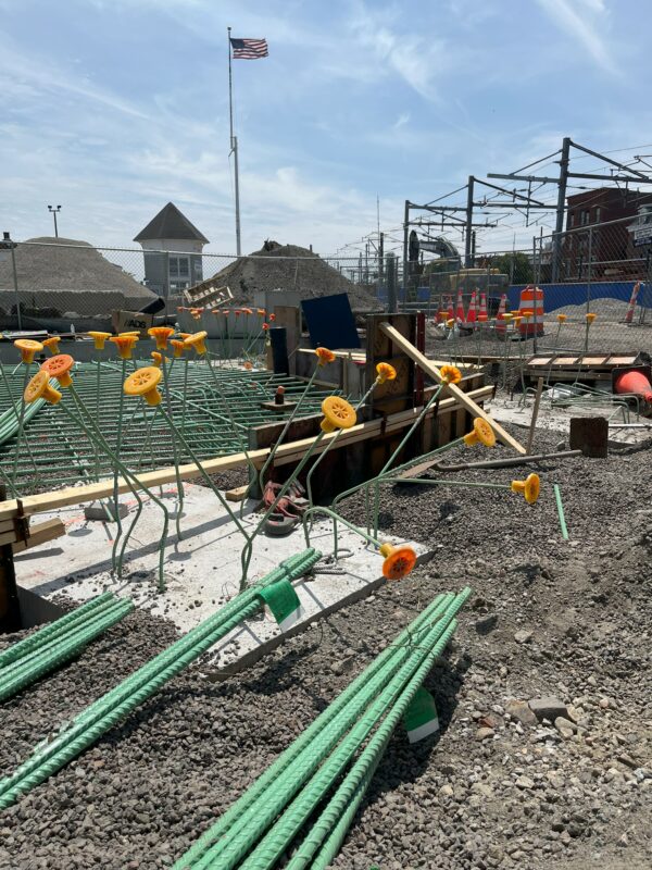 Photo: Green rebar arranged and ready for use, capped with orange safety caps.