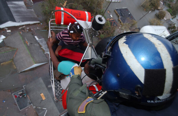 Photo: Petty Officer 1st Class Steven Huerta hoists two children into a Coast Guard rescue helicopter from a rooftop.