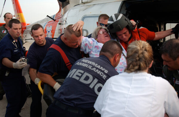 Photo: A Coast Guard helicopter rescue crew and paramedics assist a woman onto a gurney.