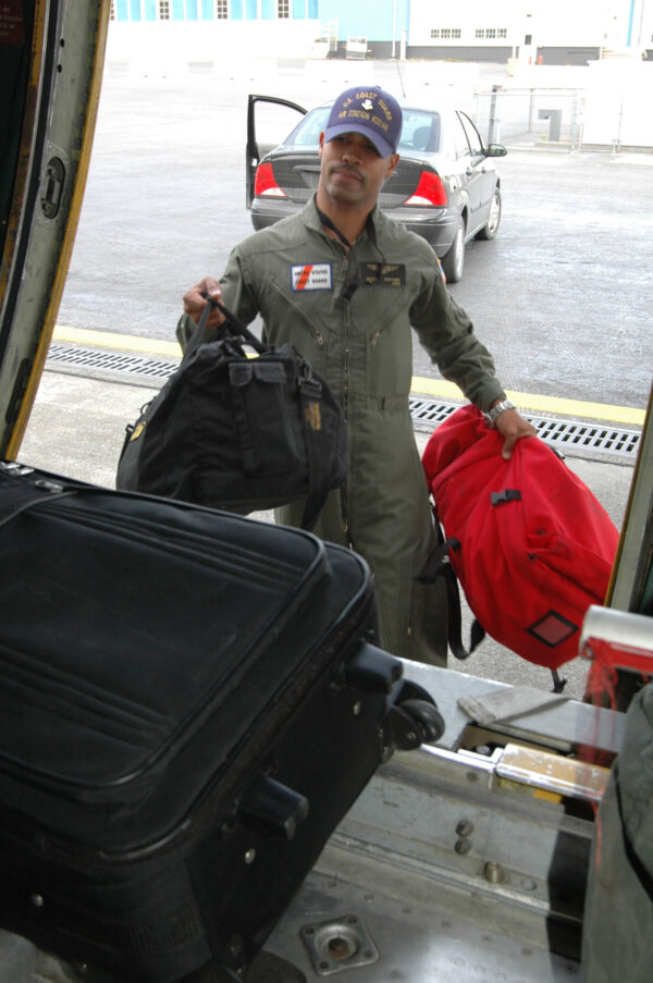 Photo: Coast Guard team member loads his luggage into a C-130 aircraft.