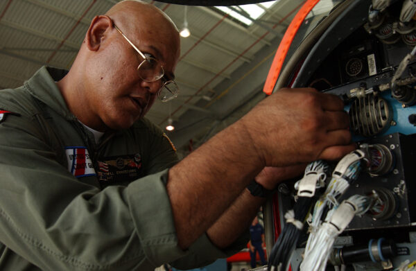 Photo: Coast Guardsman works on the electronic communications systems of an HH-65 Dolphin helicopter.