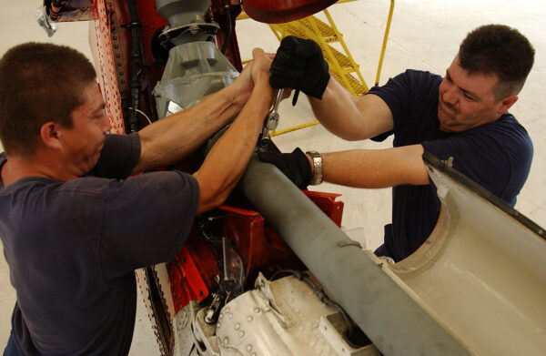 Photo: Coast Guardsmen work to repair the tail rotor drive shaft of an HH-60 Jayhawk.