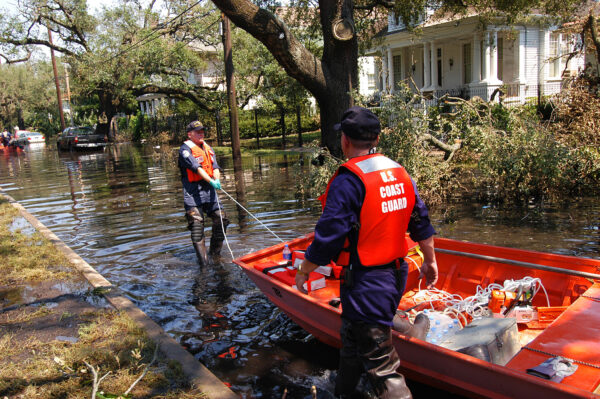 Photo: A Coast Guard search and rescue crew drags their skiff to a launching point through a flooded residential neighborhood to look for people in distress.