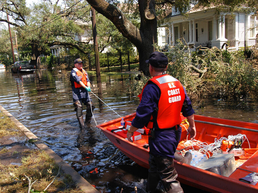 Photo: A Coast Guard search and rescue crew drags their skiff to a launching point through a flooded residential neighborhood to look for people in distress.