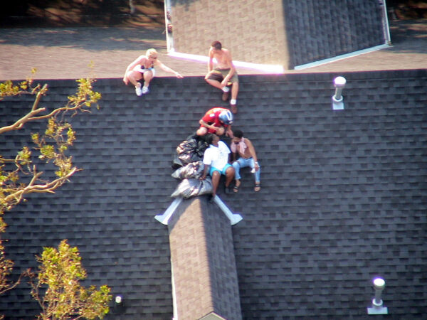 Photo: Aerial view of a rooftop where a Coast Guard rescue swimmer tells the survivors what to expect before they are lifted to safety aboard the Coast Guard HH-65C helicopter.