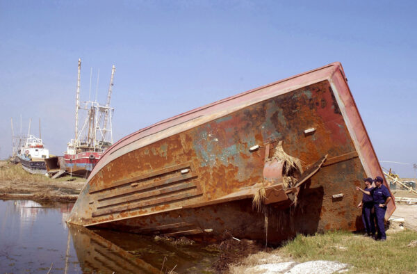 Photo: Coast Guard members examine a large shrimp boat that is grounded and on its side.