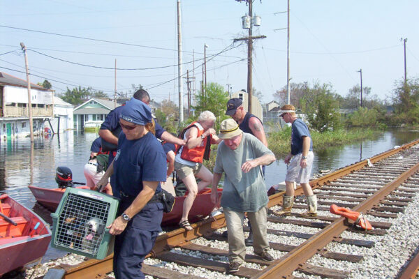 Photo: Coast Guardsmen assist residents off rescue boats along with their pets.