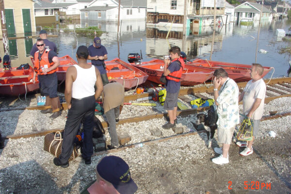 Photo: Evacuees line up with their belongings and pets near Coast Guard boats.