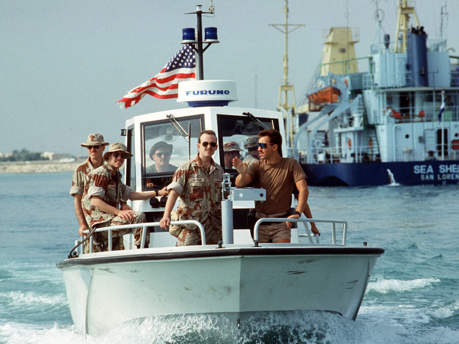 Photo: Front view of members of PSU 302 (Cleveland, Ohio) patroling the harbor aboard a Navy patrol. In the background is the short and vessel Sea Sheikh.