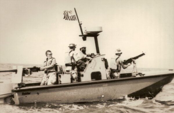 Photo: A Raider patrol boat in profile with crew ready at machine guns.