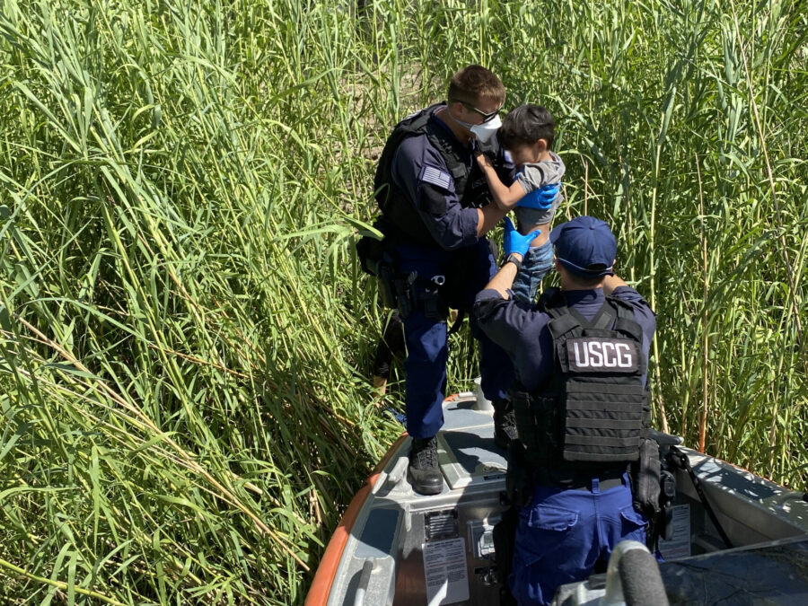 MSST member lifts a child from thick reeds on a riverbank.