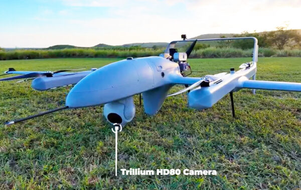 Photo: Uncrewed system (UxS), commonly known as a drone, sitting in a grassy field. The drone has a built-in high-definition camera in the front.