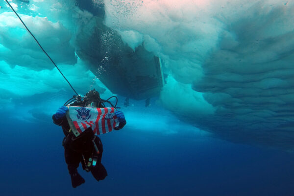 Photo: A Coast guard ice diver showing the flag while below the ice.