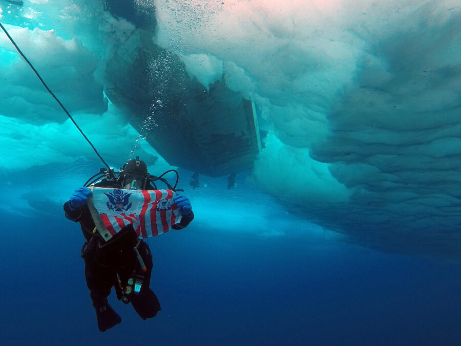 Photo: A Coast guard ice diver showing the flag while below the ice.