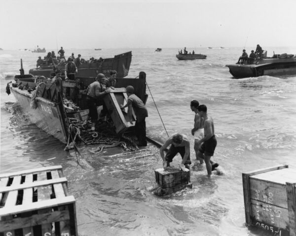 Photo: Supplies from a landing craft are unloaded in the surf.