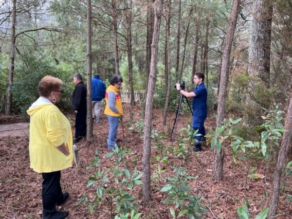 Photo: A group of people view the grave of Keeper Lewis Wescott in the woods.
