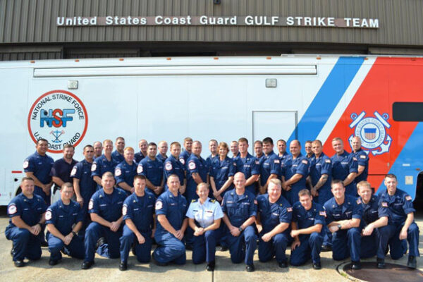 Alt: Photo: Staff at the Gulf Strike Team, Mobile, Alabama pose in front of their 18-wheeler mobile command post.