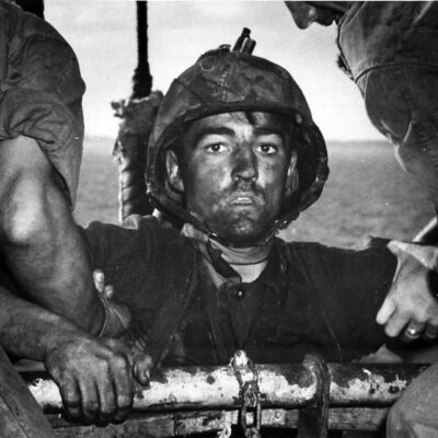 Photo: A marine looks into the camera as he is help on board.