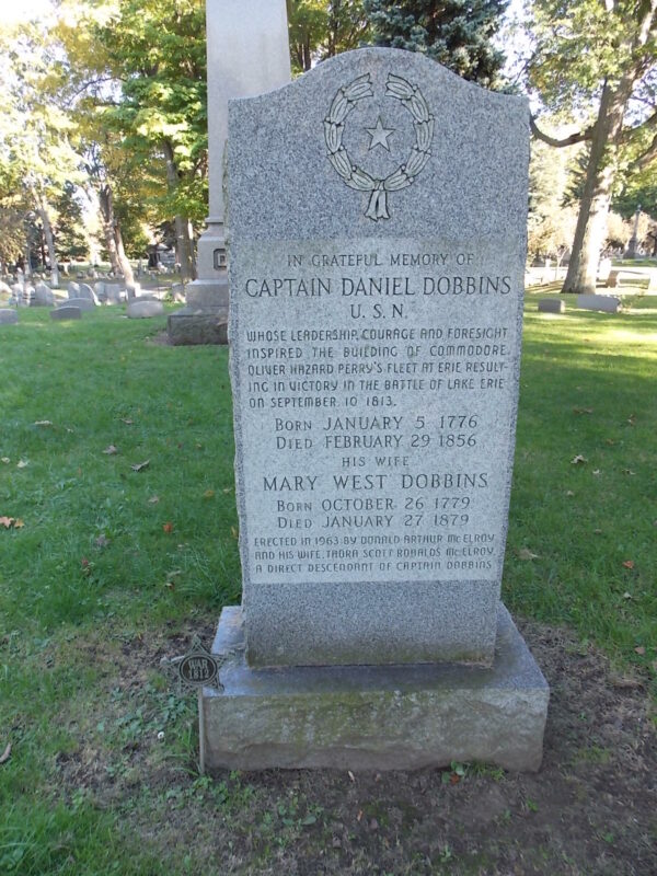 Photo: Gravestone carrying the text: In grateful memory of Captain Daniel Dobbins U.S.N. Whose leadership, courage, and foresight inspired the building of commodore Oliver Hazard Perry's fleet at Erie resulting in victory in the battle of Lake Erie on September 10, 1813. Born January 5, 1776. Died February 29, 1856. His wife, Mary West Dobbins, born October 26, 1779, died January 27, 1879. Erected in 1963 by Donald Arthur McElroy and his wife, Thora Scott Ronalds McElroy a direct descendent of Captain Dobbins.