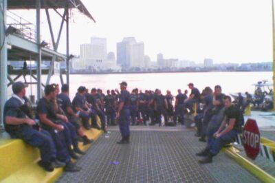 Photo: Coast Guard members assembled at ferry terminal, with river in background.