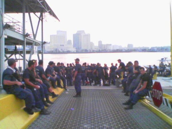 Photo: Coast Guard members assembled at ferry terminal, with river in background.