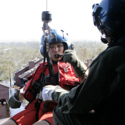 Photo: A Coast Guard aviation survival technician (AST) gives the thumbs-up signal in a helicopter while getting ready to conduct a rescue in New Orleans after Hurricane Katrina.