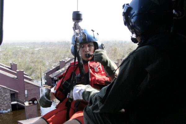 Photo: A Coast Guard aviation survival technician (AST) gives the thumbs-up signal in a helicopter while getting ready to conduct a rescue in New Orleans after Hurricane Katrina.