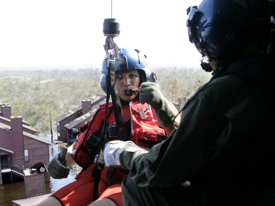 Photo: A Coast Guard aviation survival technician (AST) gives the thumbs-up signal in a helicopter while getting ready to conduct a rescue in New Orleans after Hurricane Katrina.