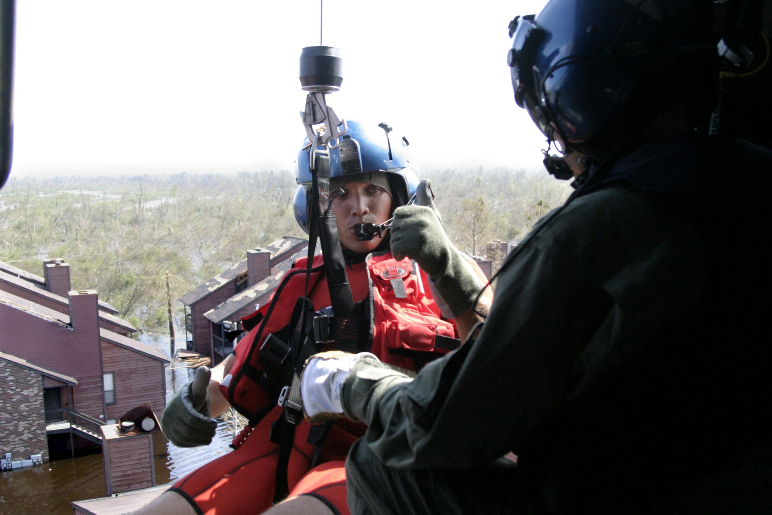 Photo: A Coast Guard aviation survival technician (AST) gives the thumbs-up signal in a helicopter while getting ready to conduct a rescue in New Orleans after Hurricane Katrina.