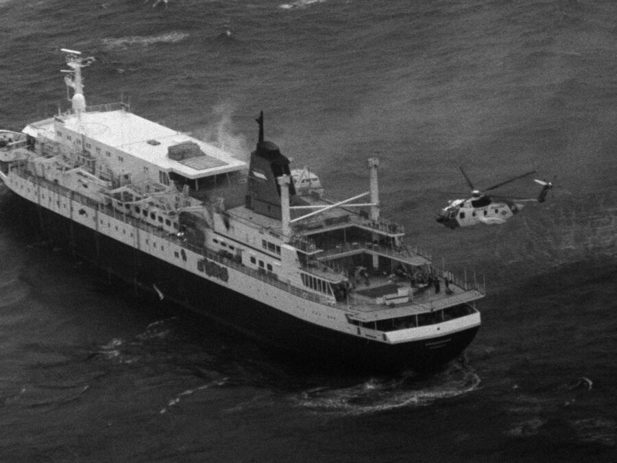 Photo: Portside aerial view of a US Coast Guard HH-3F Pelican helicopter hovers near the stern of the luxury liner Prinsendam in the Gulf of Alaska