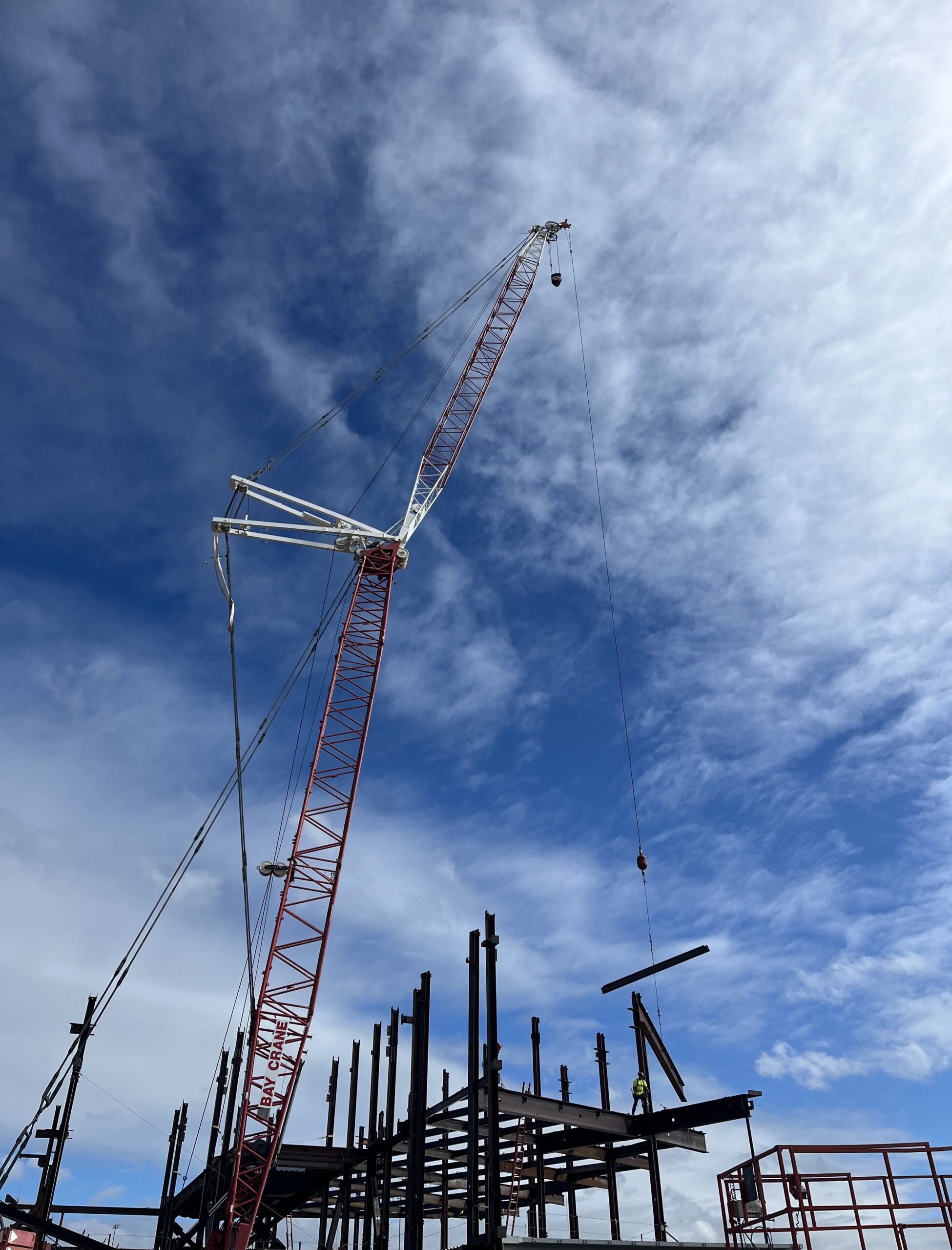 Photo: A crane towers over the steel framework as it moves beams for assembly.