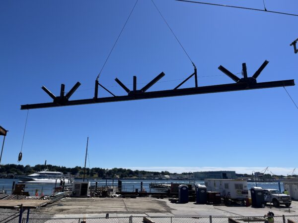 Photo: A large steel beam is lifted by a crane into place for structural assembly.