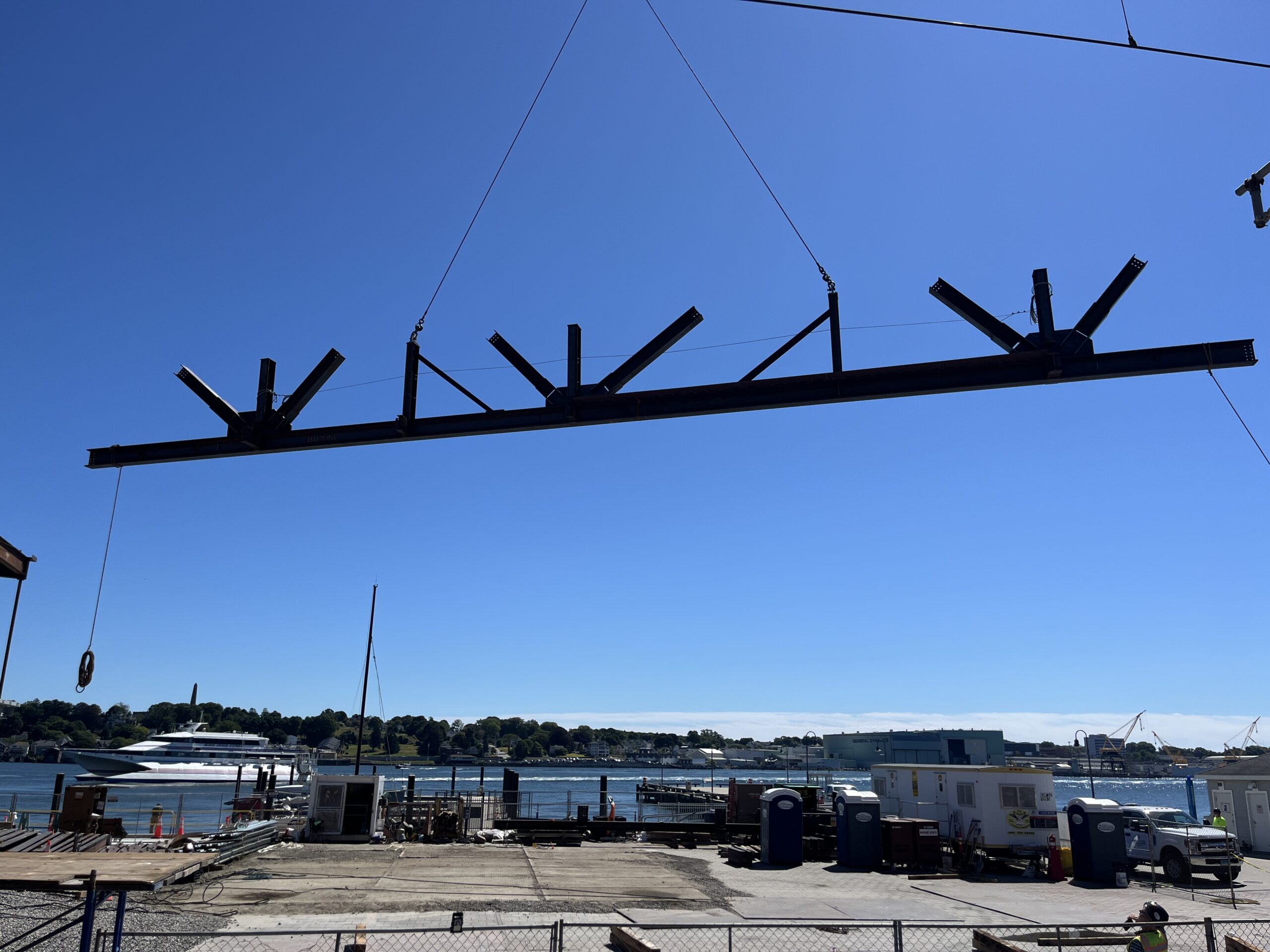 Photo: A large steel beam is lifted by a crane into place for structural assembly.