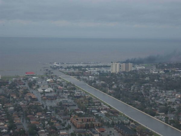 Photo: View of flooded homes and streets and homes at the bottom of a huge lake with a breached canal running through the middle.