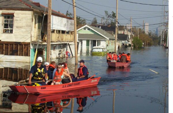 Photo: Two Coast Guard small boats on a street with flooded houses and a view of downtown New Orleans.