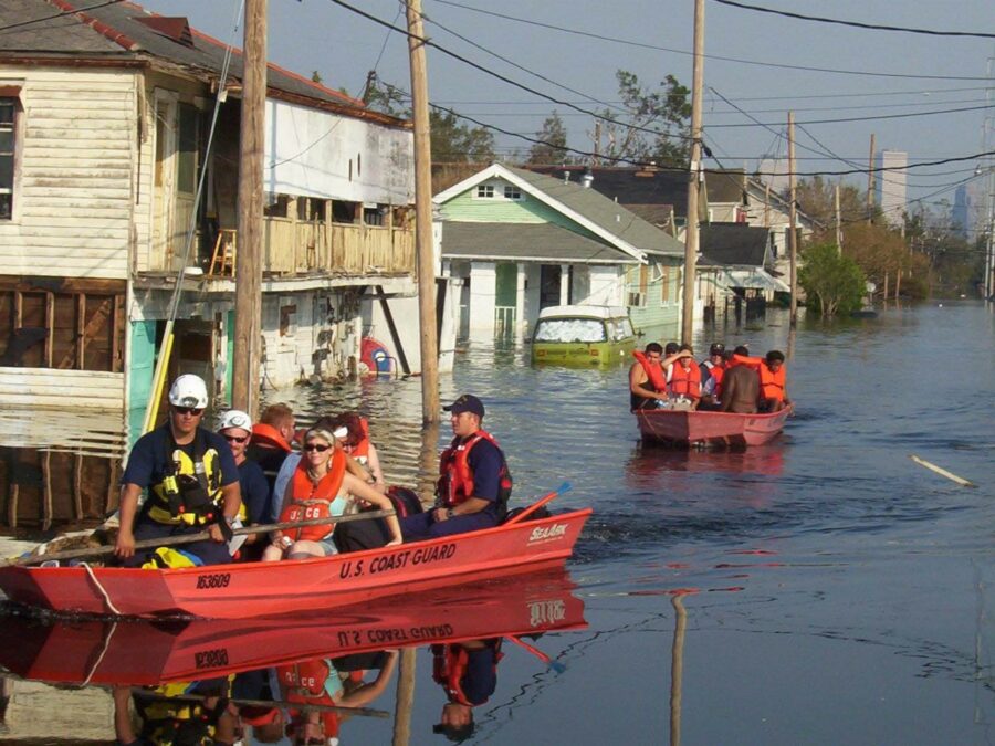 Photo: Two Coast Guard small boats on a street with flooded houses and a view of downtown New Orleans.