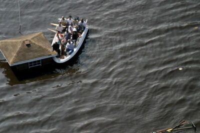 Screen capture from 'Hurricane Katrina through the eyes of Aviation'. Flood victims in boat next to a rooftop.